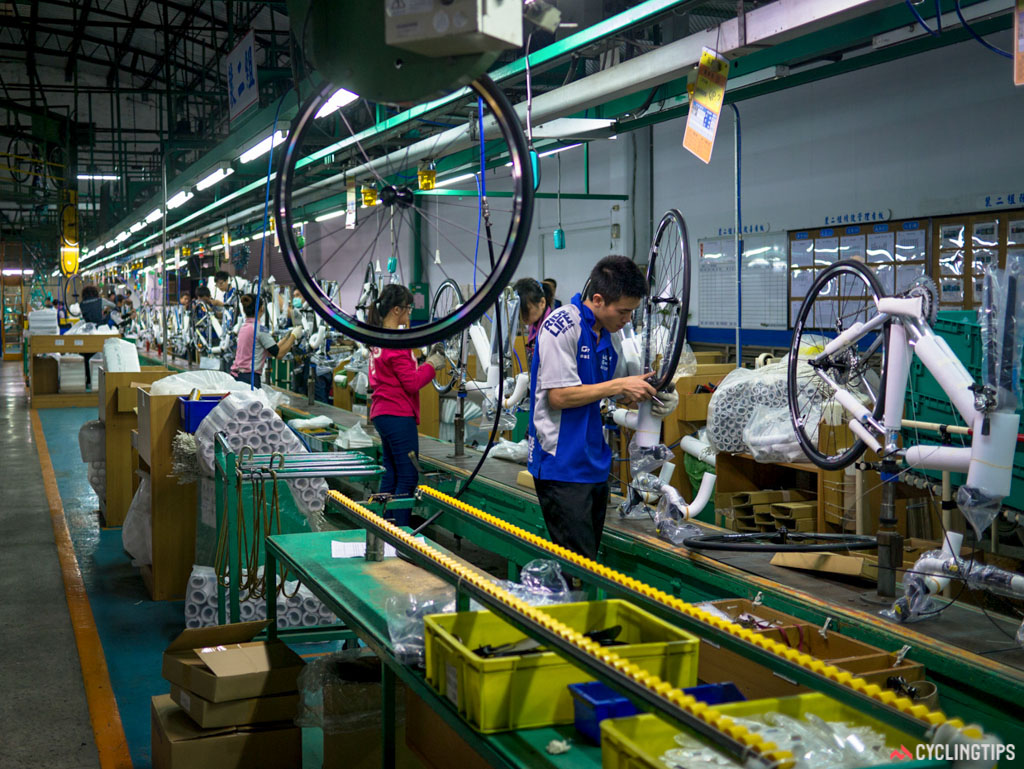 A wheel is dropped from a conveyor belt overhead into the assembly line.